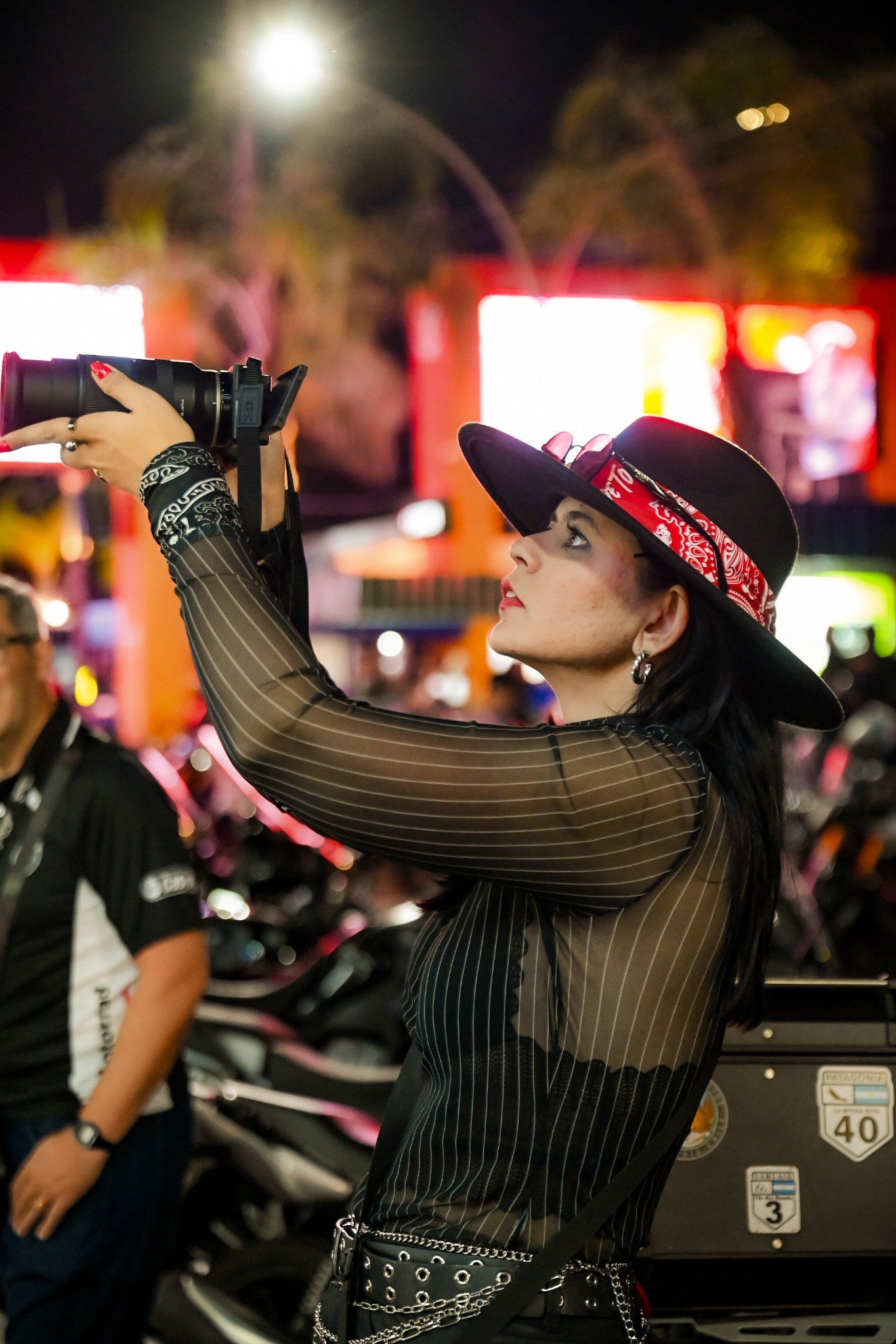 Ana Caroline fotografando com chapéu preto e bandana vermelha